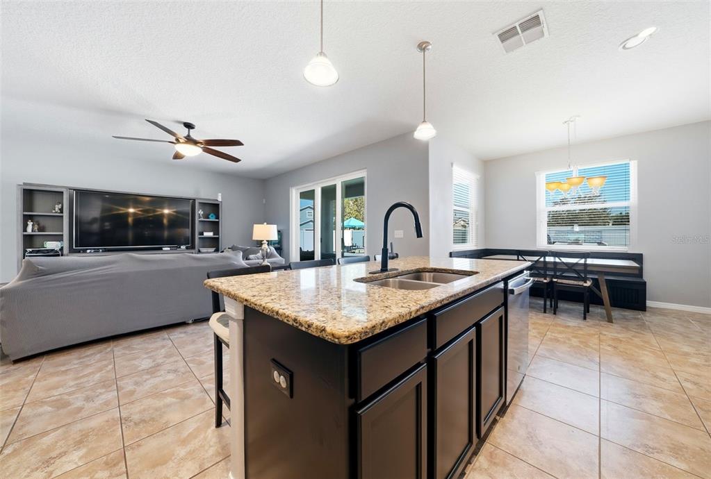 14604 Rannoch Moor Place Wimauma, FL 33598 - Photo 13 of 76 a kitchen island with granite countertop a sink a counter top space and stainless steel appliances