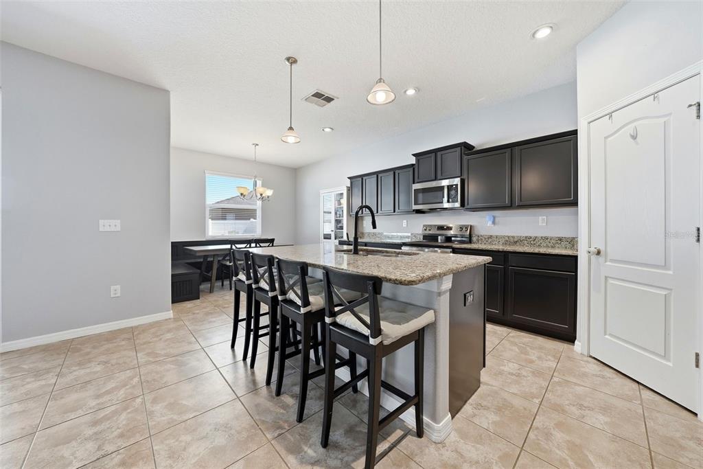14604 Rannoch Moor Place Wimauma, FL 33598 - Photo 14 of 76 a kitchen with stainless steel appliances granite countertop a stove a sink a microwave a refrigerator and cabinets