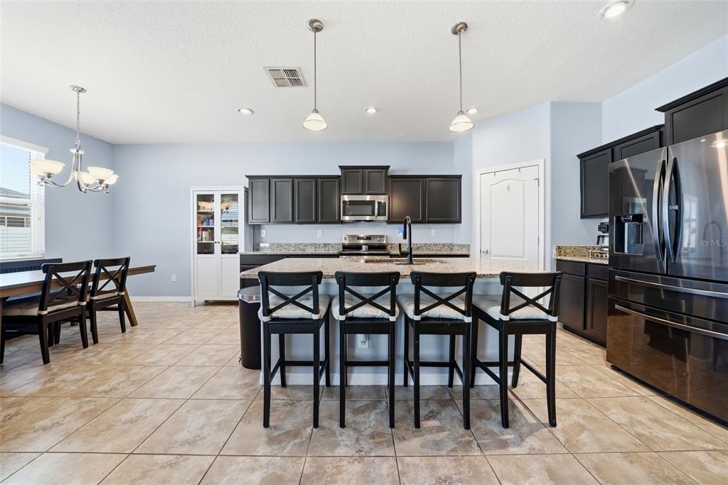 14604 Rannoch Moor Place Wimauma, FL 33598 - Photo 15 of 76 a kitchen with stainless steel appliances granite countertop a stove a refrigerator a oven a sink with a dining table and chairs