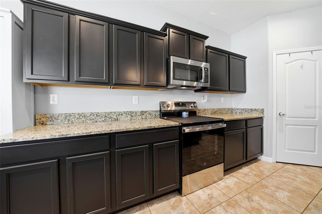 14604 Rannoch Moor Place Wimauma, FL 33598 - Photo 17 of 76 a kitchen with stainless steel appliances granite countertop a stove and a microwave