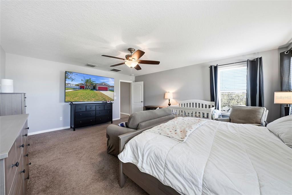 14604 Rannoch Moor Place Wimauma, FL 33598 - Photo 37 of 76 a spacious bedroom with a bed and a chandelier