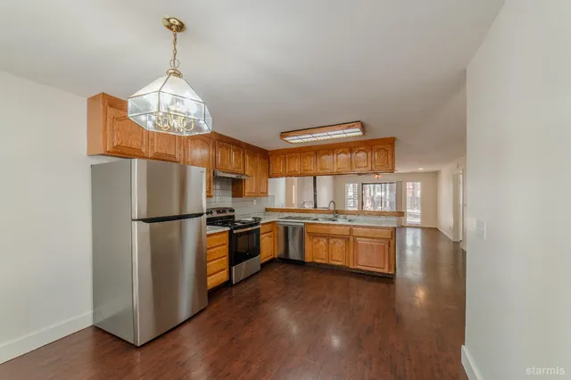 a open kitchen with stainless steel appliances granite countertop a stove refrigerator a sink dishwasher and a microwave oven with wooden floor