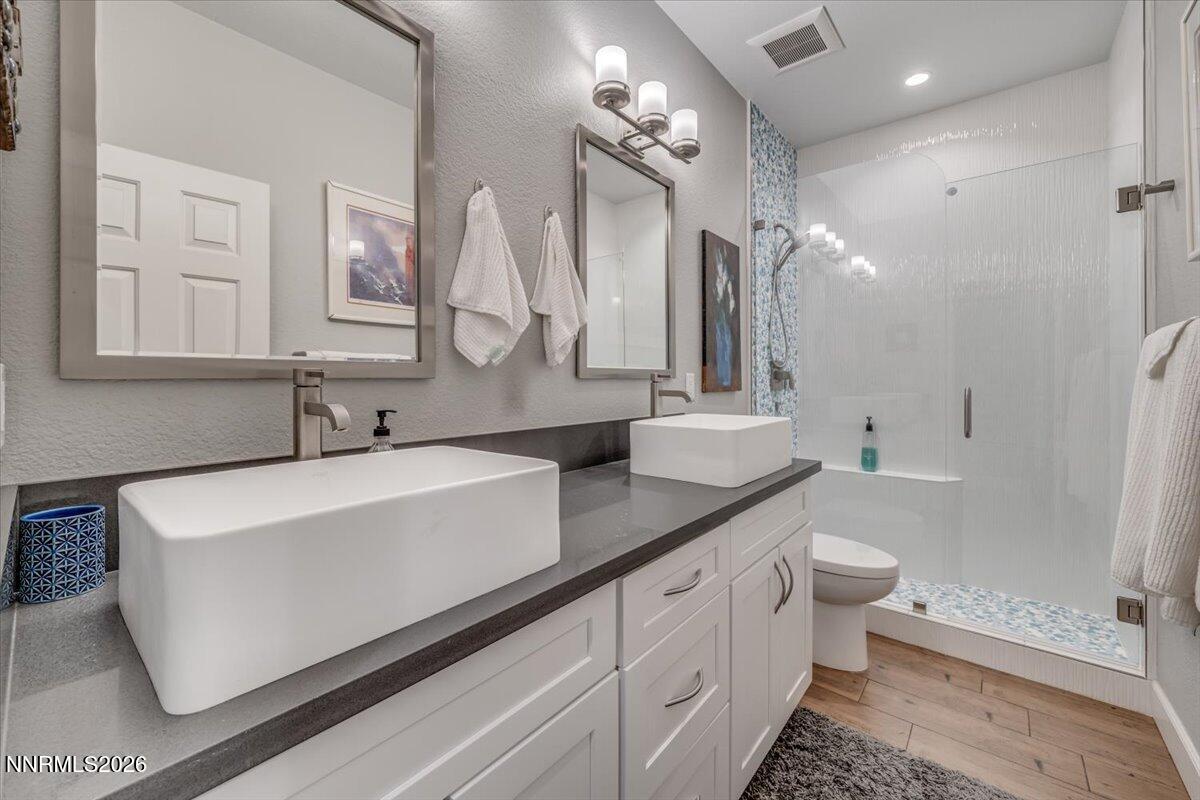 10562 Thistle Berry Court Reno, NV 89521 - Photo 34 of 44 a large white bathroom with a double vanity sink a toilet a mirror and shower
