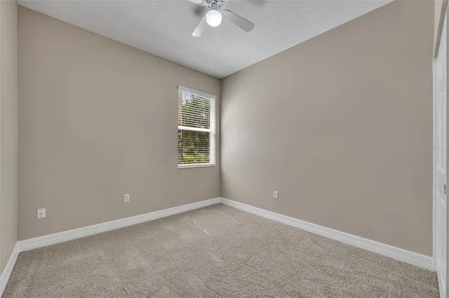 an empty room with a window and a ceiling fan