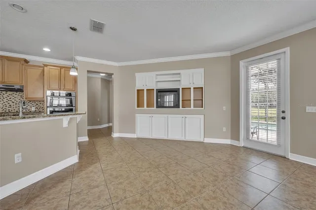 a view of an empty room with kitchen and window