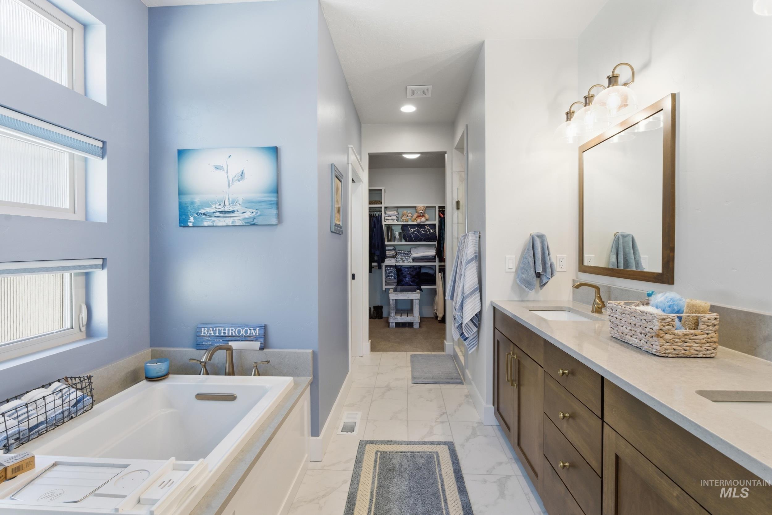 6347 South Utmost Lane Meridian, ID 83642 - Photo 22 of 37 Bathroom featuring a built-in tub with deck-mounted faucet, a double vanity with undermount sinks, bronze-finish fixtures, and a framed mirror