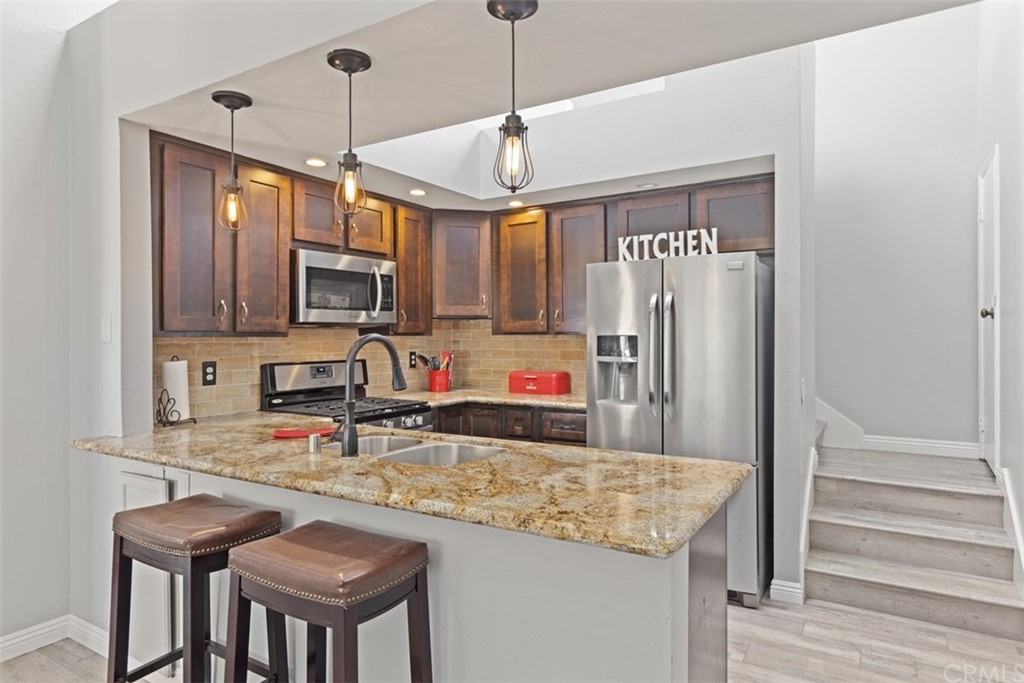 19 Brisa Ribera Rancho Santa Margarita, CA 92688 - Photo 6 of 16 a kitchen with stainless steel appliances granite countertop a stove top oven a sink dishwasher a dining table and chairs with wooden floor