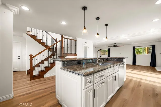 a kitchen with stainless steel appliances granite countertop a kitchen island a stove a sink and a wooden floors