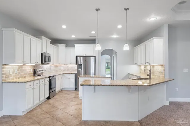 a large kitchen with kitchen island a sink a center island stainless steel appliances and cabinets