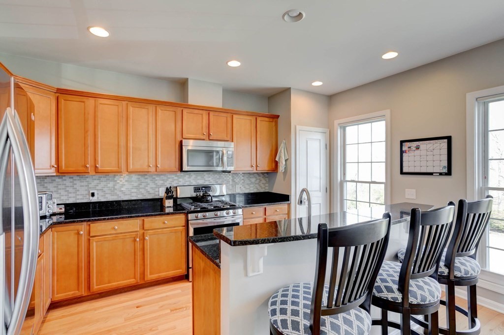 31 Jacob Way, Unit 31 Reading, MA 01867 - Photo 20 of 42 a kitchen with stainless steel appliances granite countertop a stove top oven a sink dishwasher a dining table and chairs with wooden floor