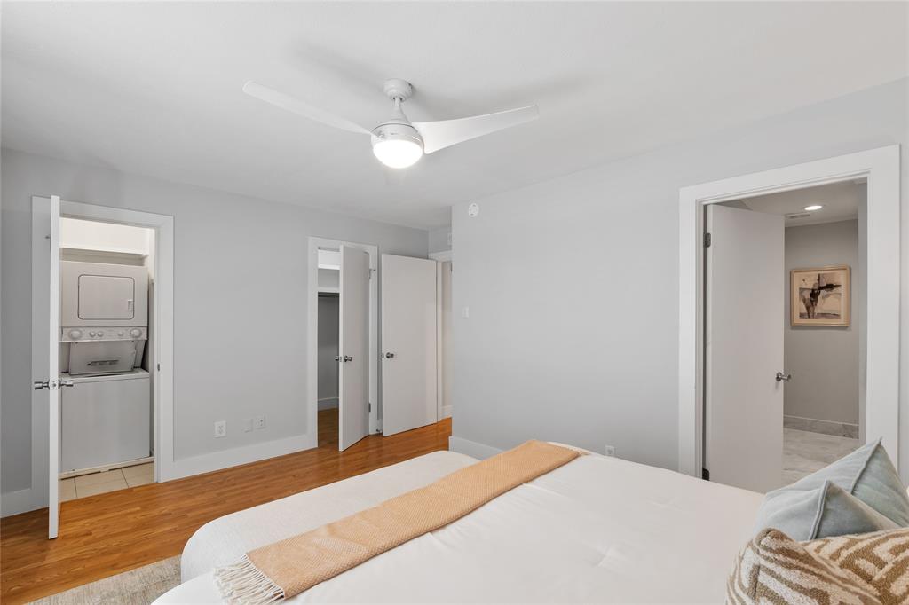 10727 Villager Road, Unit C Dallas, TX 75230 - Photo 24 of 39 Bedroom featuring estacked washer and dryer, wood finished floors, connected bathroom, a walk in closet, and ceiling fan