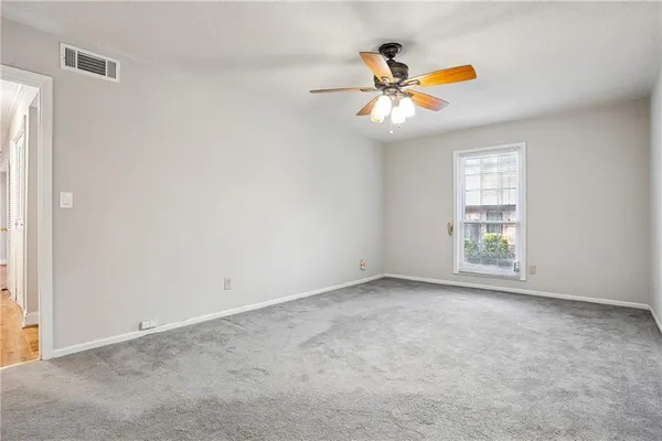 an empty room with windows and fan