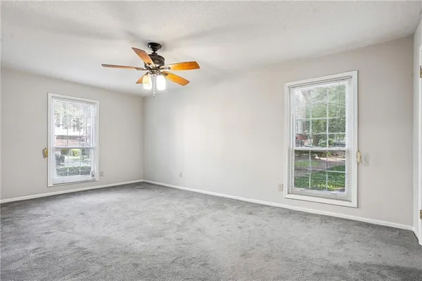 an empty room with windows and fan