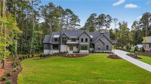 a front view of a house with a garden and trees