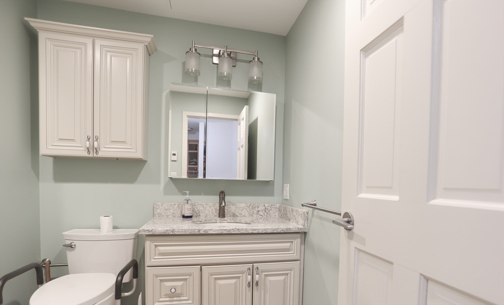 100 Keyes Road, Unit 220 Concord, MA 01742 - Photo 14 of 23 a bathroom with a granite countertop sink vanity mirror and toilet