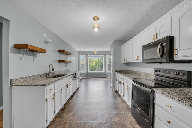 a kitchen with granite countertop a sink and stove top oven