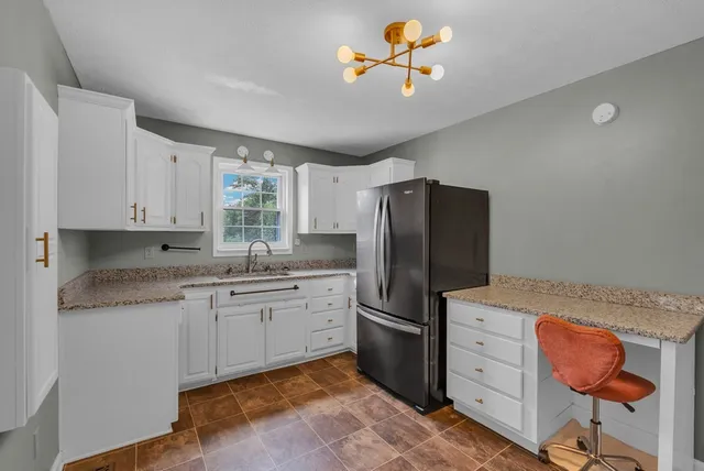 a kitchen with stainless steel appliances granite countertop a sink a stove a refrigerator cabinets and a dining table