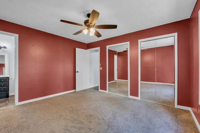 an empty room with closet and a chandelier fan