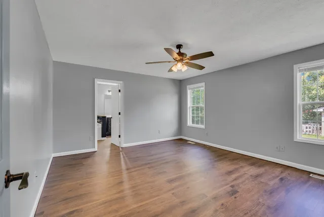 an empty room with wooden floor and windows