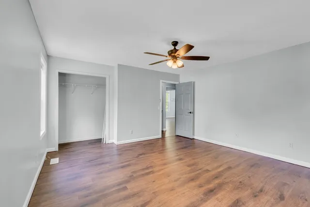 a view of an empty room with wooden floor and chandelier