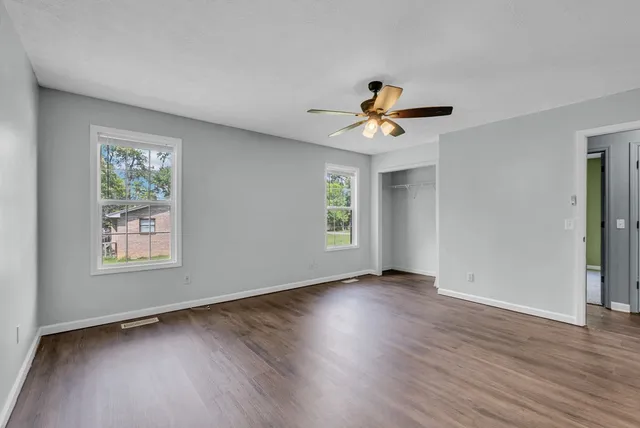 an empty room with wooden floor and windows