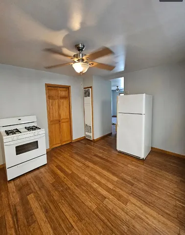 a view of a kitchen with a stove a ceiling fan and wooden floor