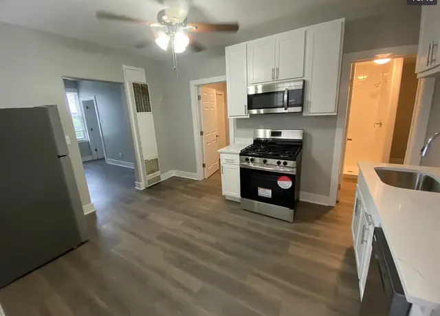 a kitchen with granite countertop a refrigerator a stove top oven a sink and dishwasher