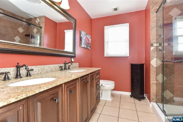 a bathroom with a granite countertop sink a toilet a mirror and shower