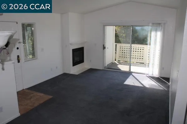 a view of an empty room with a fireplace and a window