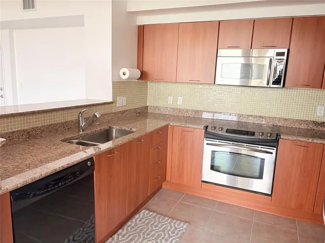 a kitchen with granite countertop a sink stainless steel appliances and cabinets