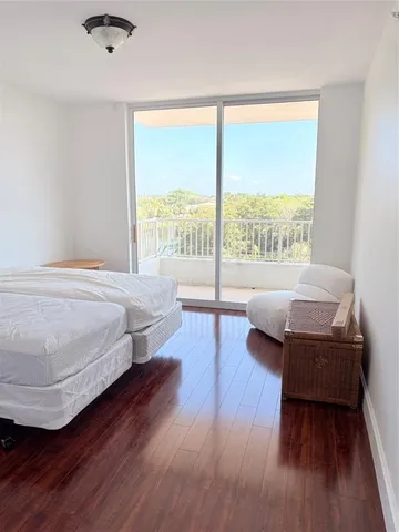 a bedroom with a bed wooden floor and a large window