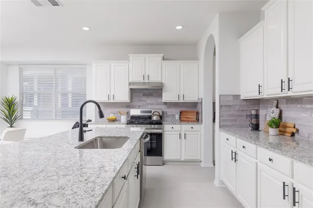 a kitchen with stainless steel appliances granite countertop lots of white cabinets a sink and dishwasher