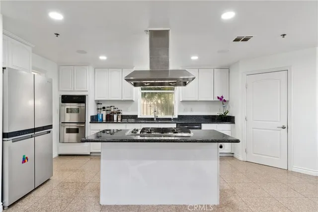 a kitchen with kitchen island stainless steel appliances a stove refrigerator sink and cabinets