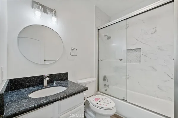 a bathroom with a granite countertop sink toilet mirror and shower