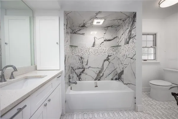 a bathroom with a granite countertop sink a toilet and shower curtain
