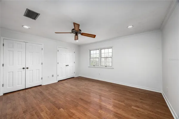 a view of empty room with wooden floor and fan