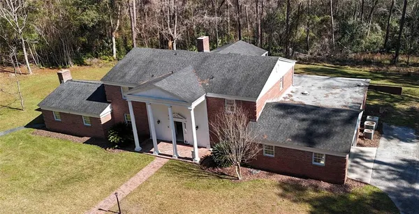 an aerial view of a house with swimming pool and large trees