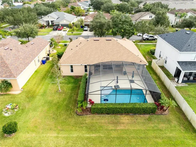 an aerial view of a house with swimming pool and large trees