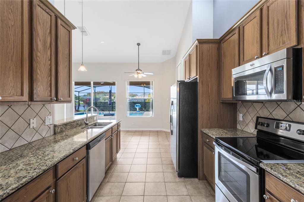 3510 Pawleys Loop South St. Cloud, FL 34769 - Photo 7 of 32 a kitchen with stainless steel appliances granite countertop a sink stove and refrigerator