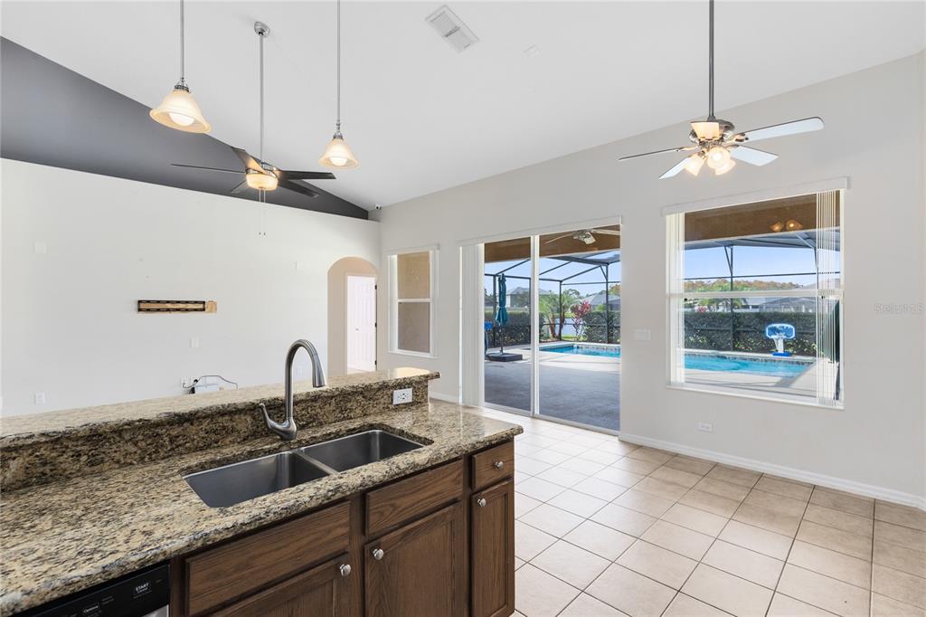 3510 Pawleys Loop South St. Cloud, FL 34769 - Photo 8 of 32 a kitchen with granite countertop a sink a counter top space and living room view
