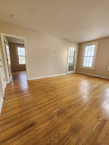 a view of an empty room with window and wooden floor