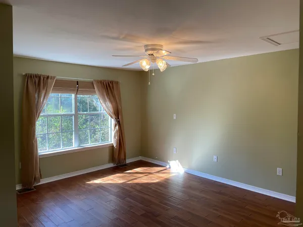 an empty room with wooden floor and windows