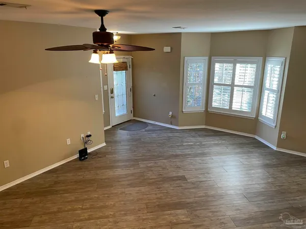 a view of an empty room with window and wooden floor