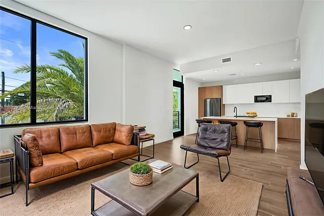 a living room with furniture kitchen view and a large window