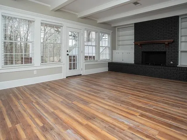 a view of an empty room with wooden floor and a fireplace