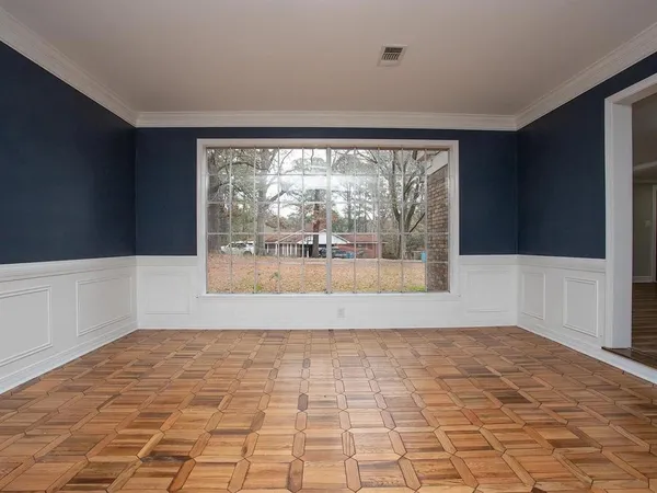 a view of empty room with wooden floor and fan