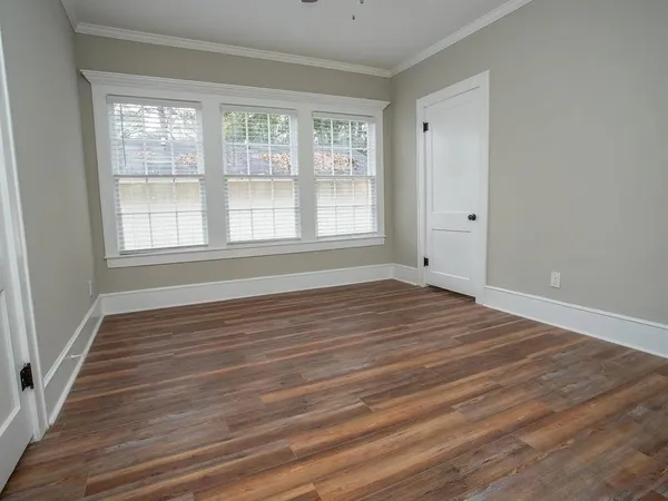 a view of an empty room with wooden floor and a window