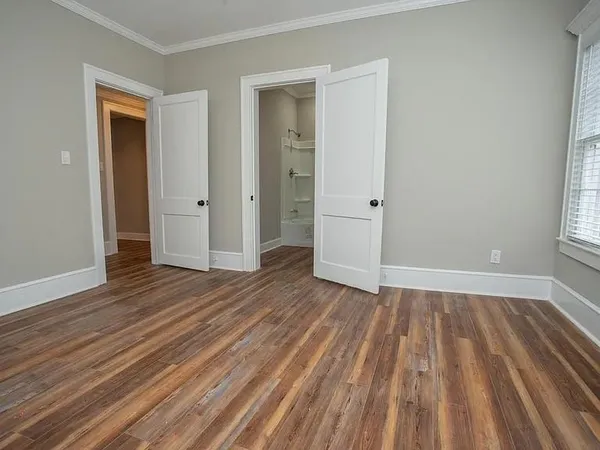 a view of an empty room with wooden floor and a window