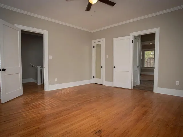 an empty room with ceiling fan and windows