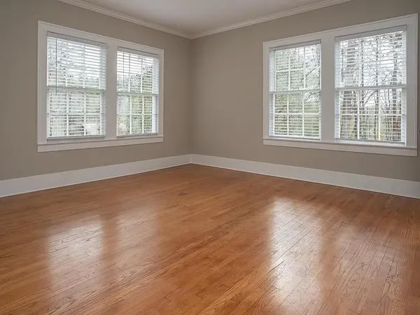 a view of an empty room with wooden floor and a window
